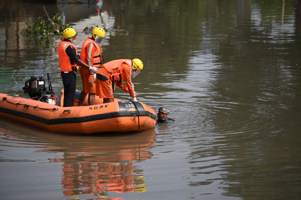 A National Disaster Response Force diver holds on a dinghy as they inspect the area where some shanty houses collapsed into a canal due to heavy rains in New Delhi on July 19, 2020. (Photo by Sajjad HUSSAIN / AFP) (Photo by SAJJAD HUSSAIN/AFP via Getty Images)