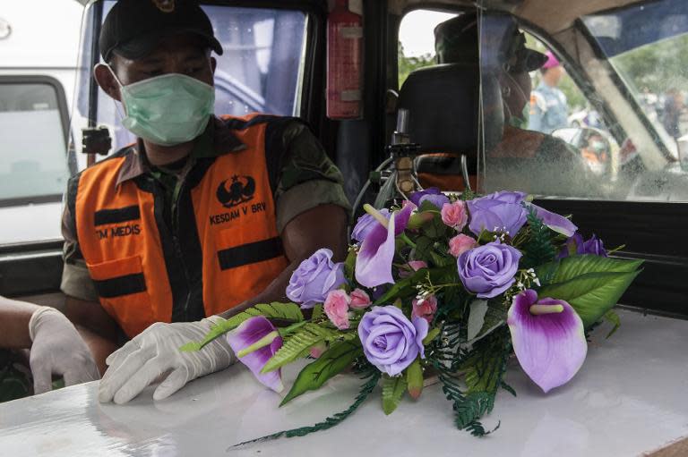 An Indonesian officer sits next to a coffin containing the body of a passenger from AirAsia Flight QZ8501 in Surabaya on January 3, 2015