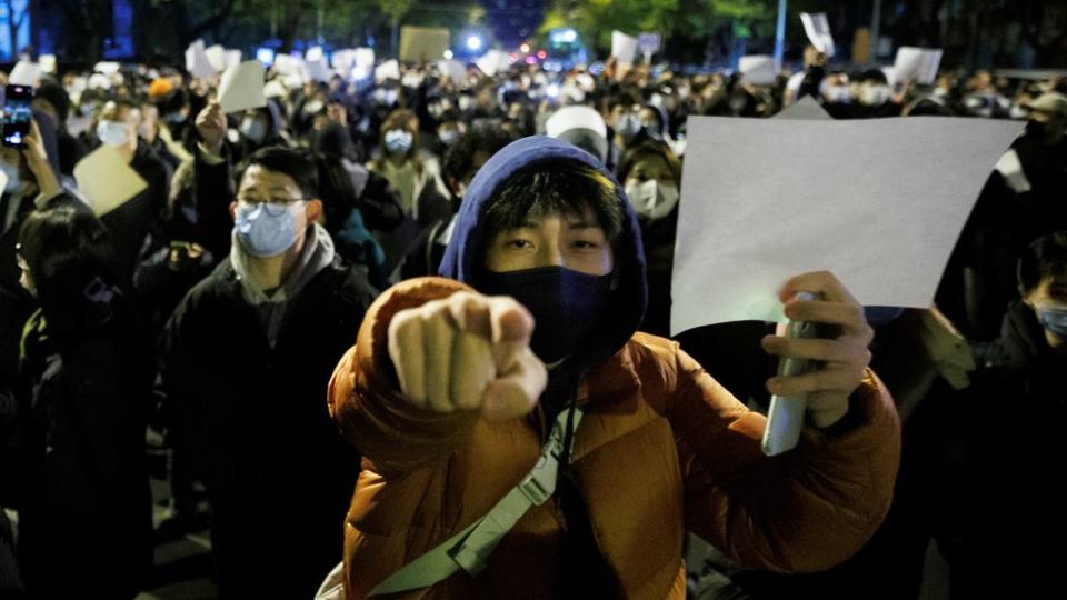 Joven portando una hoja en blanco en manifestación en Pekín.