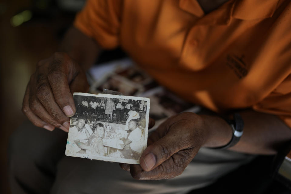 Barber Glenn Paige, 69, displays an old family photograph showing his father, left, and mother enjoying a band at Club Eaton, which opened during segregation and in its heyday became a venue for the country's most celebrated Black musicians, as Paige waits for his next client at Blessed by the Best barbershop in Eatonville, Fla., Thursday, Aug. 24, 2023. Paige treasures Eatonville's unique history as a self-governing Black municipality, and preserved two bricks from the now demolished Robert Hungerford Normal and Industrial School which he plans to decorate with the school's name and dates of operation and display in his shop. (AP Photo/Rebecca Blackwell)