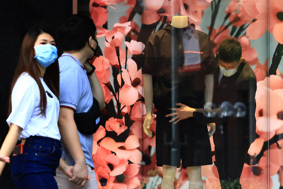 A worker wearing a protective mask prepares a window display at a Prada boutique at Orchard Road on 20 June, 2020, in Singapore. (PHOTO: Getty Images)