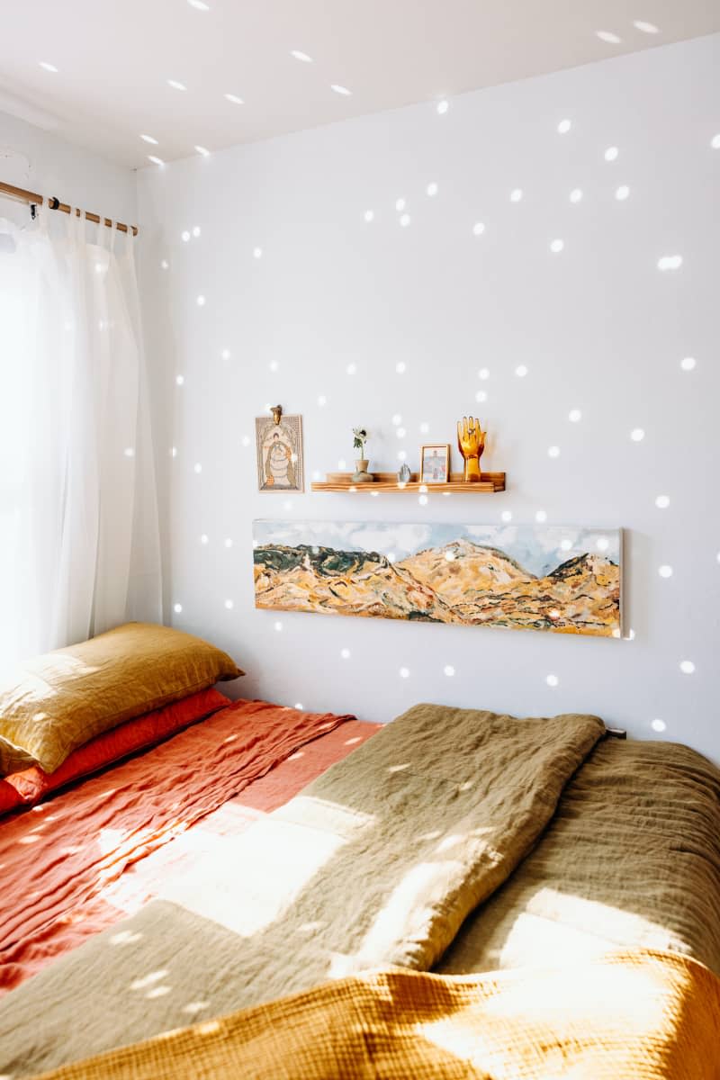 Art is hung on wall next to bed with earth tone bedding.