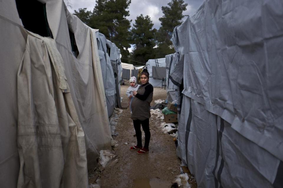 In this Sunday, Jan. 1, 2017 photo, Sa'da Bahjat, 20 and 9 months pregnant, a Syrian refugee from al-Hasaka, holds her daughter Yamoor, 11 months, while posing for a picture by the entrance of her shelter, at the refugee camp of Ritsona, Greece. "Our situation in Greece is very bad, no one is paying us attention, we are abandoned here, I wish someone would turn to us with help", Bahjat said. Squalid conditions and subfreezing temperatures in Greece’s migrant camps this winter are taking their toll on everyone living in them with expectant mothers and babies especially feel the brunt. (AP Photo/Muhammed Muheisen)