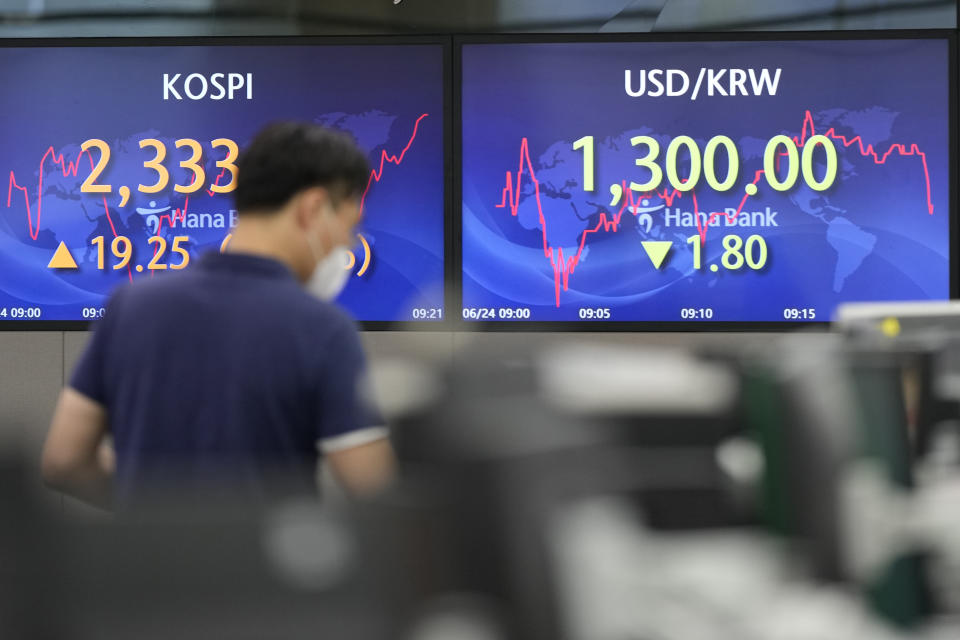 A currency trader walks by the screens showing the Korea Composite Stock Price Index (KOSPI), left, and the foreign exchange rate between U.S. dollar and South Korean won at a foreign exchange dealing room in Seoul, South Korea, Friday, June 24, 2022. Shares were higher in Asia on Friday, tracking gains on Wall Street, where the market is headed for its first weekly gain after three weeks of punishing losses. (AP Photo/Lee Jin-man)