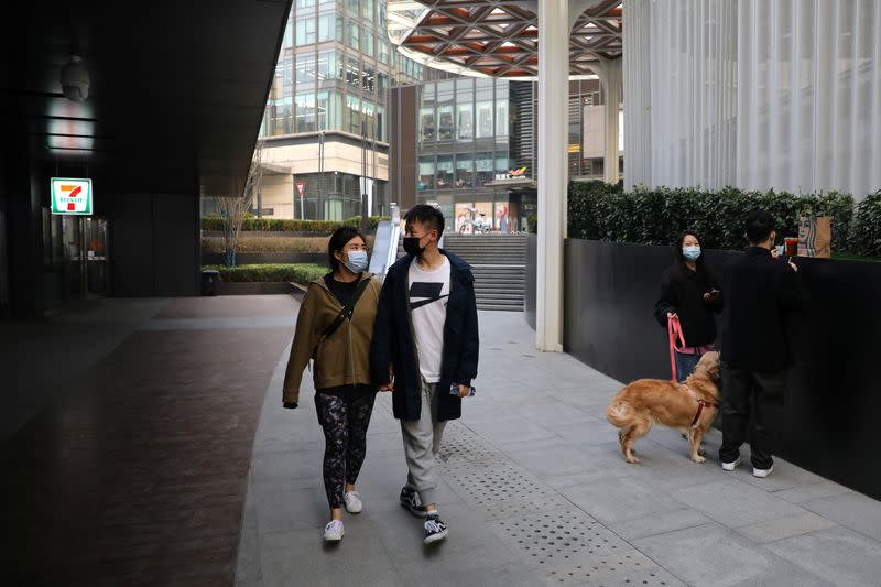 Married couple Liu Zhichang and Yu Tao walk at a plaza after they finished gym class in Beijing