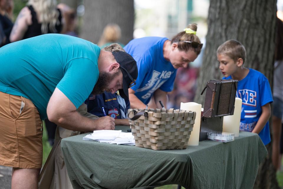 Families write out thoughts and memories of the Dunham family at a memorial Saturday night at Hartville Memorial Park.