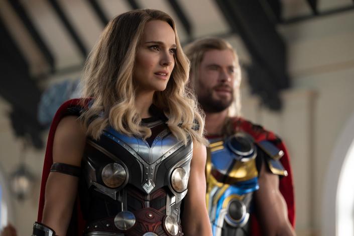 Natalie Portman standing in front of Chris Hemsworth, both wearing Thor costumes