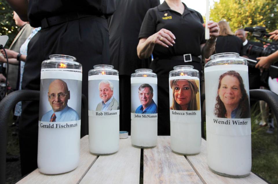In this June 29, 2018, file photo, pictures of five employees of the Capital Gazette newspaper adorn candles during a vigil across the street from where they were slain in the newsroom in Annapolis.  Jarrod Ramos pleaded guilty in 2019 to all 23 counts against him in the attack at the Capital Gazette nearly three years ago, but he has pleaded that he is not criminally responsible due to mental illness.
