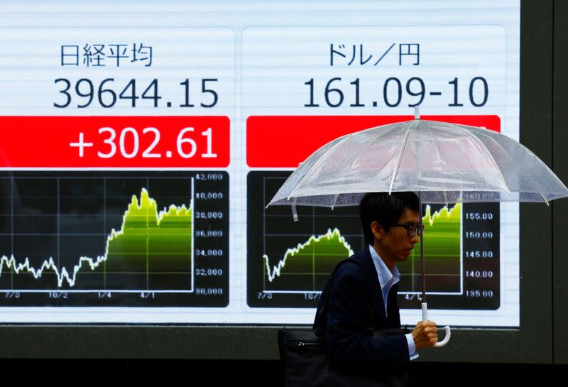 A person walks past an electric screen displaying the current Japanese Yen exchange rate against the U.S. dollar in Tokyo