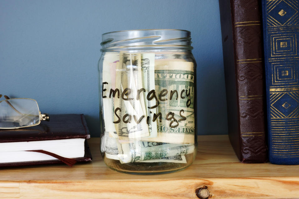 Glass jar filled with bills and labeled emergency savings