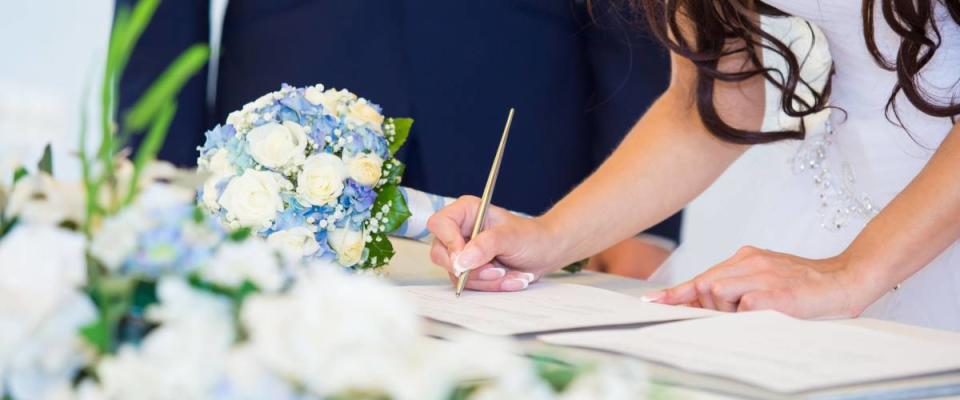 Bride hand with a pen signing wedding license