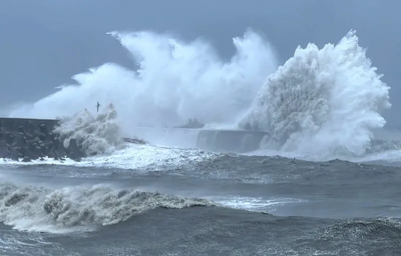 颱風小犬過境，5日長浪打在富岡港的堤防激起約20米高浪花，左邊的燈柱被吞噬。（中央社）