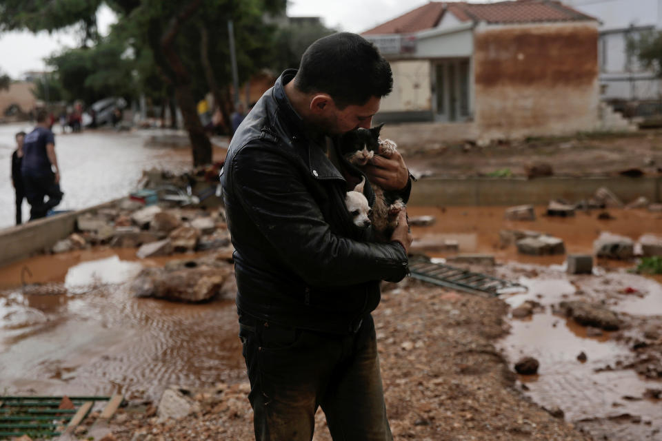 A local, carrying a dog in his jacket, holds a cat he saved from a tree, following a heavy rainfall in the town of Mandra. (Photo: Alkis Konstantinidis/Reuters)