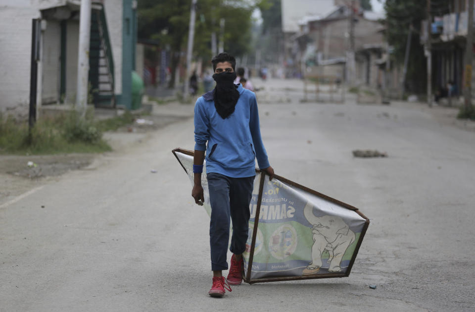 A Kashmiri protester drags an advertisement hoarding to be used as a shield during an anti-India protest Srinagar, India, Friday, Aug. 9, 2019. The predominantly Muslim area has been under an unprecedented security lockdown and near-total communications blackout to prevent unrest and protests after India's Hindu nationalist-led government said Monday it was revoking Kashmir’s special constitutional status and downgrading its statehood. (AP Photo/Altaf Qadri)