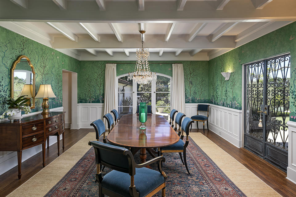 The dining room exudes traditional glamour with antique furnishings and emerald-green wallcoverings.
