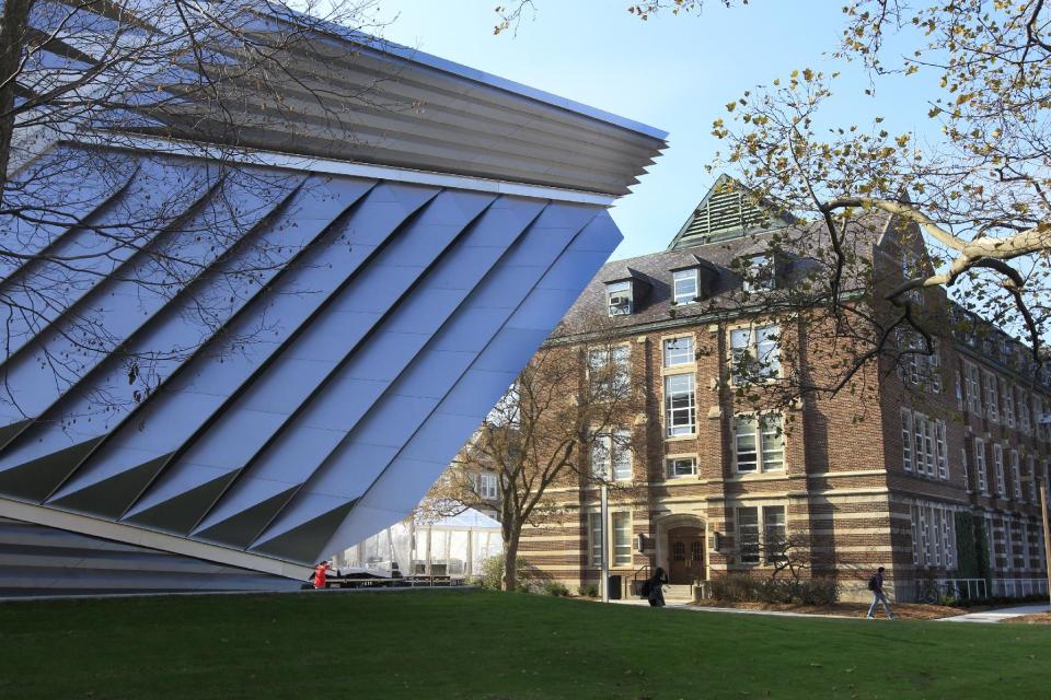 In this Nov. 9, 2012 photo a portion of the Eli and Edythe Broad Art Museum, left, is seen on the campus of Michigan State University in East Lansing, Mich. The museum features Zaha Hadid's signature look: a facade of pleated stainless steel and glass, which distinguishes it from the traditional brick Collegiate Gothic buildings that surround it on Michigan State's north campus. (AP Photo/Carlos Osorio)