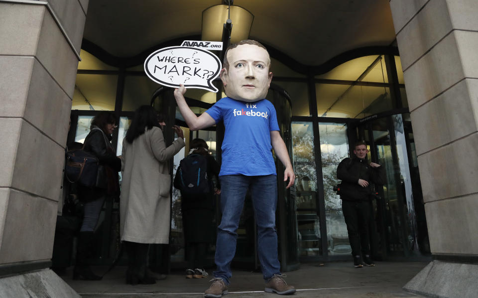 An activist wearing a Facebook CEO Mark Zuckerberg mask stands in front of Portcullis House in Westminster as an international committee of parliamentarians met for a hearing on the impact of disinformation on democracy in London, Tuesday, Nov. 27, 2018. Lawmakers from nine countries grilled a Facebook executive who came in place of Zuckerberg on Tuesday as part of an international hearing at Britain's parliament on disinformation and "fake news."  (AP Photo/Frank Augstein)