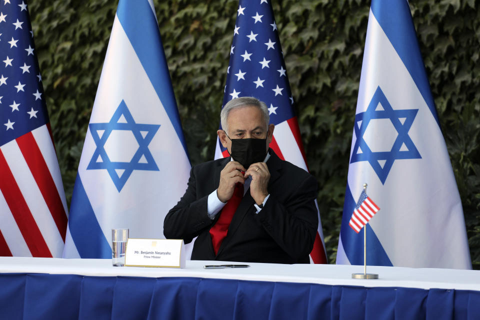 Israeli Prime Minister Benjamin Netanyahu adjusts his face mask during a ceremony to sign amendments to a series of scientific cooperation agreements with U.S. Ambassador to Israel David Friedman, at Ariel University, in the West Bank settlement of Ariel, Wednesday, Oct. 28, 2020. The United States and Israel amended the agreements on Wednesday to include Israeli institutions in the West Bank, a step that further blurs the status of settlements widely considered illegal under international law. (Emil Salman/Pool via AP)