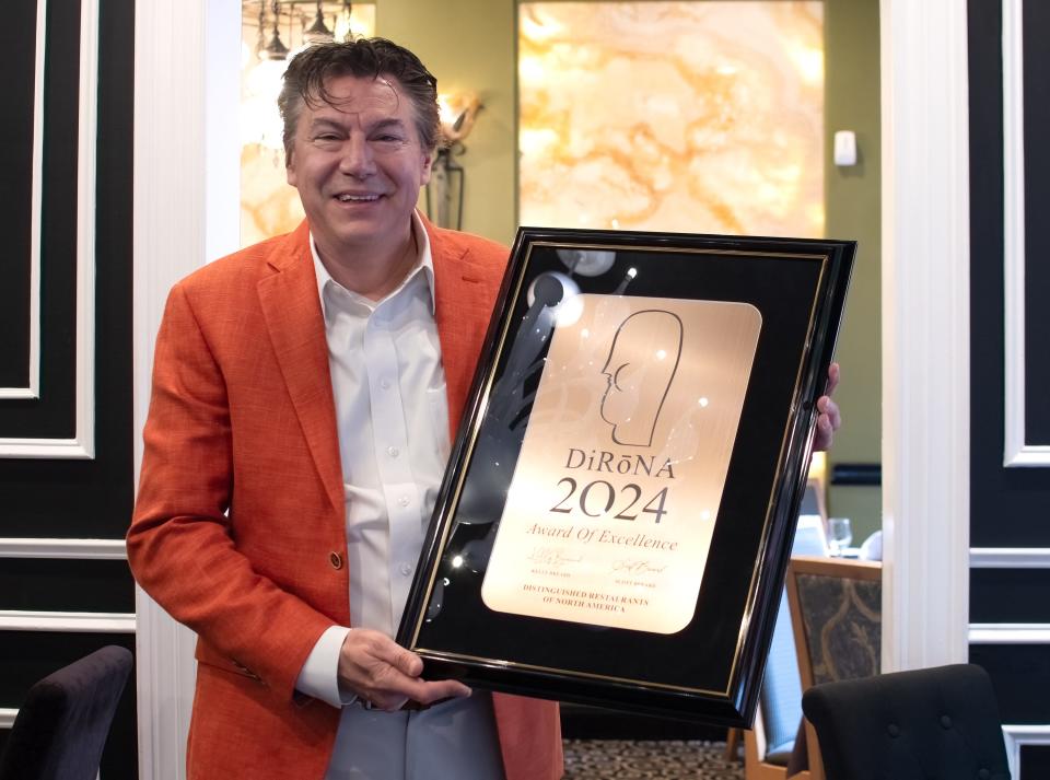 Alex Litras, owner of Café Margaux in Cocoa Village, holds the restaurant's new Distinguished Restaurants of North America DiRōNA ‘Gold’ Award of Excellence.