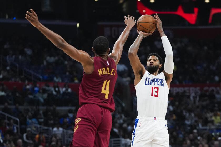 Los Angeles Clippers forward Paul George, right, shoots past Cleveland Cavaliers forward Evan Mobley (4) during the second half of an NBA basketball game, Sunday, April 7, 2024, in Los Angeles. (AP Photo/Ryan Sun)