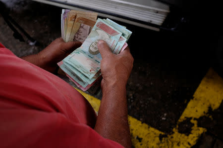 A gas station worker counts Venezuelan bolivar notes at a gas station of the Venezuelan state-owned oil company PDVSA in Caracas, Venezuela September 24, 2018. REUTERS/Marco Bello