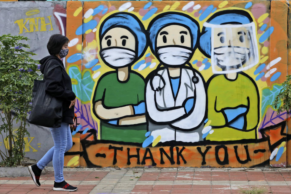 A woman walks past a mural honoring health care workers during the new coronavirus outbreak in Jakarta, Indonesia, Thursday, May 28, 2020. (AP Photo/Dita Alangkara)