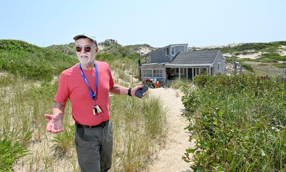 In this June 2023 photo, Peter Clemons stands before his family's Provincetown dune shack which they call The Grail.