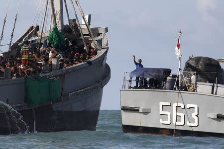 A Myanmar military officer (R) gestures from a navy ship towards a boat packed with migrants, off Leik Island in the Andaman Sea May 31, 2015. REUTERS/Soe Zeya Tun
