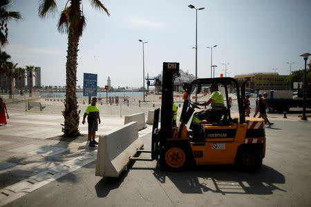 Workers place concrete barriers to prevent possible attacks on the walk "Muelle Uno" a day after a van crashed into pedestrians at Las Ramblas, outside town hall in Malaga, Spain August 18, 2017. REUTERS/Jon Nazca