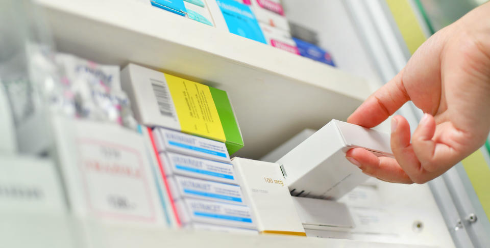 Closeup pharmacist hand holding medicine box in pharmacy drugstore.