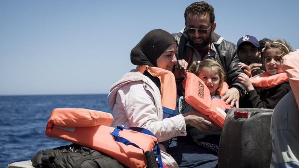 Adults and children wearing life vests on a boat