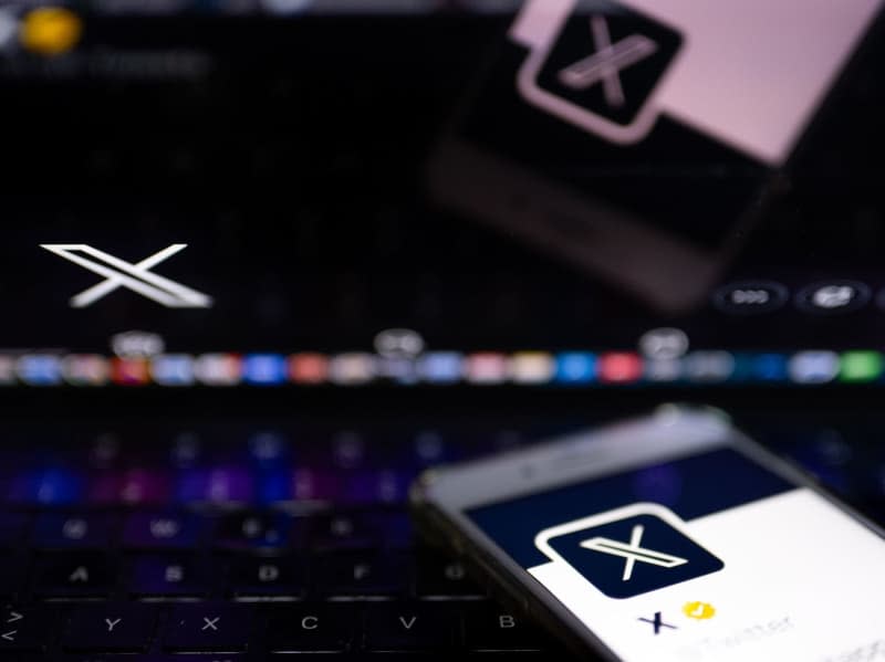 The white letter X can be seen on a black background on the official profile of the X platform on the screen of a smartphone and on the display of a laptop. Monika Skolimowska/dpa