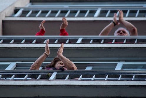 <span class="caption">People clap from a balcony during a collective scheduled clapping event in honor of workers of the sanitary and health sector in Orense, northwest Spain, 29 March 2020. </span> <span class="attribution"><span class="source">EPA/Brais Lorenzo</span></span>