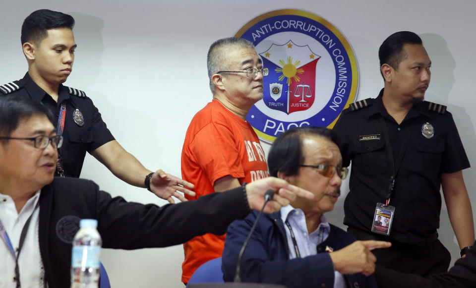 Xie Haojie, center, who was arrested in an operation coordinated with Chinese authorities, is turned over by Philippine Immigration Chief Jaime Morente, seated left, and Presidential Anti-Corruption Commission chief Dante Jimenez, seated right, to La Yifan, China's Director for International Cooperation of the Central Commission for Discipline Inspection during a news conference in Manila, Philippines Wednesday, Jan. 16, 2019. Philippine officials have turned over to China the former government official wanted for alleged economic crime and corruption. (AP Photo/Bullit Marquez)