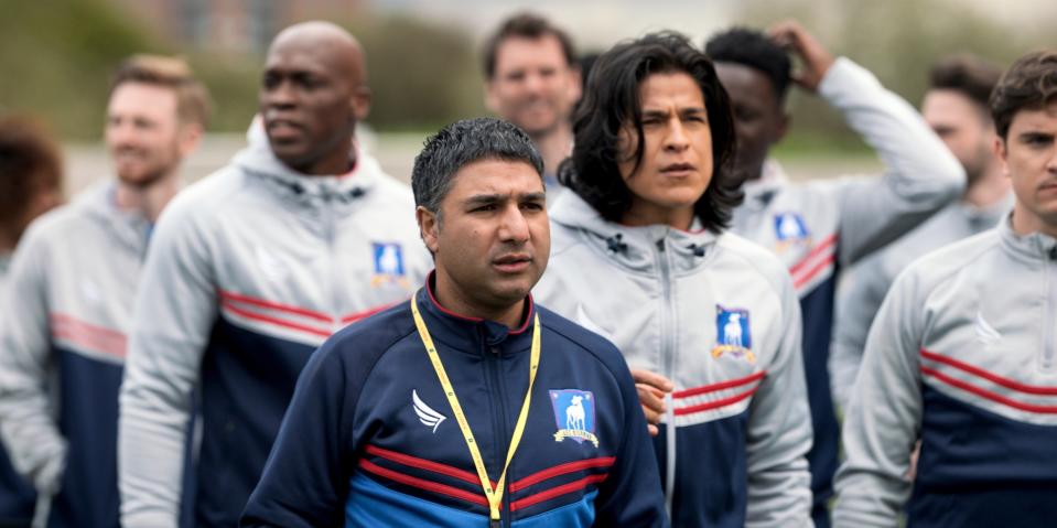 A group of soccer players listening attentively with a coach in the foreground