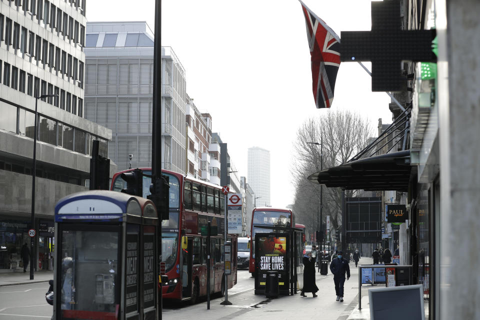 A coronavirus information sign is displayed by a bus stop with a Union flag above in London, Friday, Jan. 15, 2021, during England's third national lockdown since the coronavirus outbreak began. The U.K. is under an indefinite national lockdown to curb the spread of the new variant, with nonessential shops, gyms and hairdressers closed, most people working from home and schools largely offering remote learning. (AP Photo/Matt Dunham)