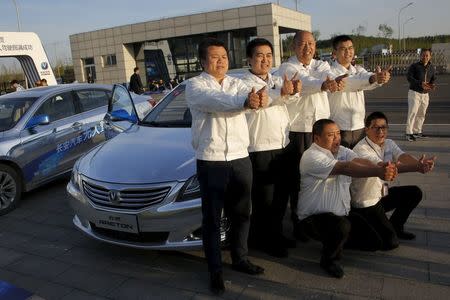 Members of Changan Automobile's self-driving car development team pose for pictures in front of their self-driving cars after the cars completed a test drive from Chongqing to Beijing, China, April 16, 2016. REUTERS/Kim Kyung-Hoon