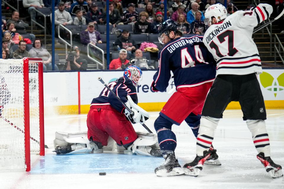 Dec 31, 2022; Columbus, Ohio, USA;  Columbus Blue Jackets goaltender Joonas Korpisalo (70) looks over his shoulder after making s ave while Chicago Blackhawks center Jason Dickinson (17) and Columbus Blue Jackets defenseman Erik Gudbranson (44) contest the puck during the second period of the NHL hockey game between the Columbus Blue Jackets and the Chicago Blackhawks at Nationwide Arena on Saturday afternoon.