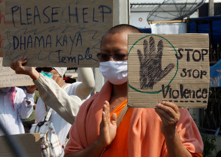 Buddhist monks speak with policeman as they gather at the gate of Dhammakaya temple in Pathum Thani province, Thailand February 20, 2017. REUTERS/Chaiwat Subprasom