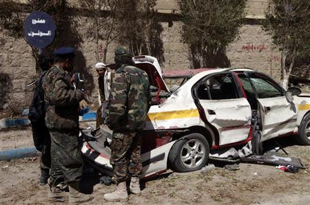 Police examine a damaged car near the central prison in Sanaa February 14, 2014. REUTERS/Mohamed al-Sayaghi