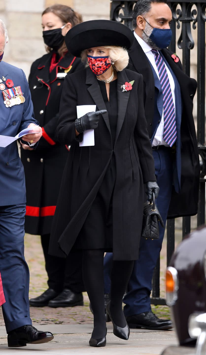 <p>Camilla paired an all-black look with pearl strands and a structured black hat for a commemoration of the Centenary of the Burial of the Unknown Warrior at Westminster Abbey. She adorned the look with a symbolic poppy brooch and a matching poppy-print face mask.</p>