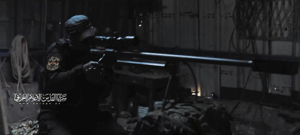 In this image from a propaganda video released by Hamas in October 2023, a masked fighter poses with a large sniper rifle. Weapons experts told The Associated Press the gun is an Iranian-made AM-50 Sayyad, which fires a .50- caliber round powerful enough to punch through up to an inch of steel. The AM-50 has previously been spotted on battlefields in Yemen, Syria, and in the hands of Shia militias in Iraq. Watermark at left reads, "Quds Brigades military media." (Hamas via AP)