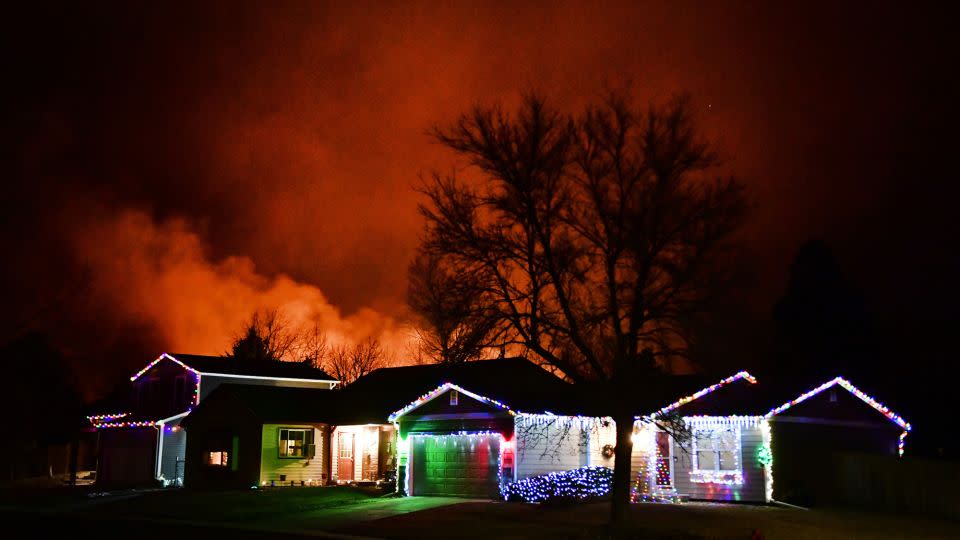 Christmas lights adorn a house as the Marshall Fire rages in the background on December 30, 2021, in Louisville, Colorado. - Helen H. Richardson/MediaNews Gr/Denver Post/Getty Images