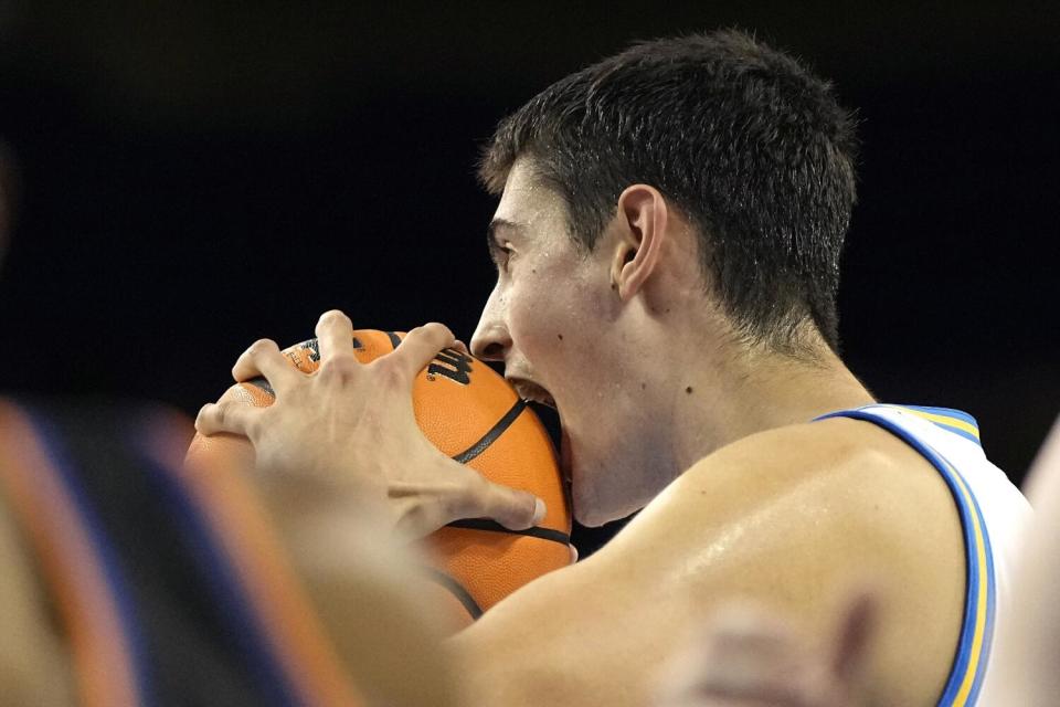 UCLA center Aday Mara holds his mouth open against a basketball.