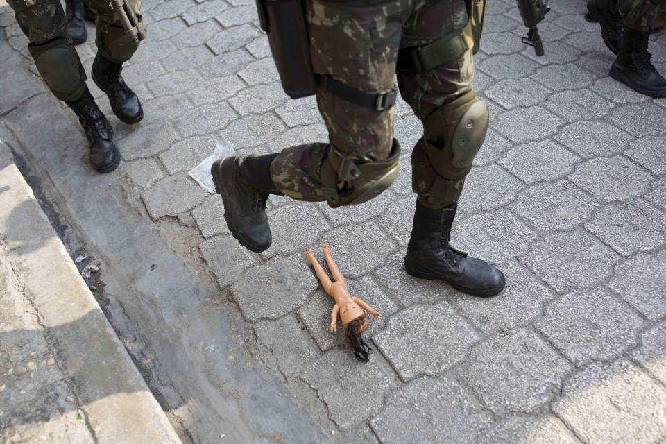 In this Feb. 22, 2017 photo, a U.N. peacekeeper from Brazil sidesteps an abandoned doll left on a street of the Cite Soleil slum in Port-au-Prince, Haiti. The peacekeepers have earned praise for boosting security, paving the way to elections and providing crucial support after disasters. But some troops have also been accused of excessive force, rape and abandoning babies they fathered. (AP Photo/Dieu Nalio Chery)