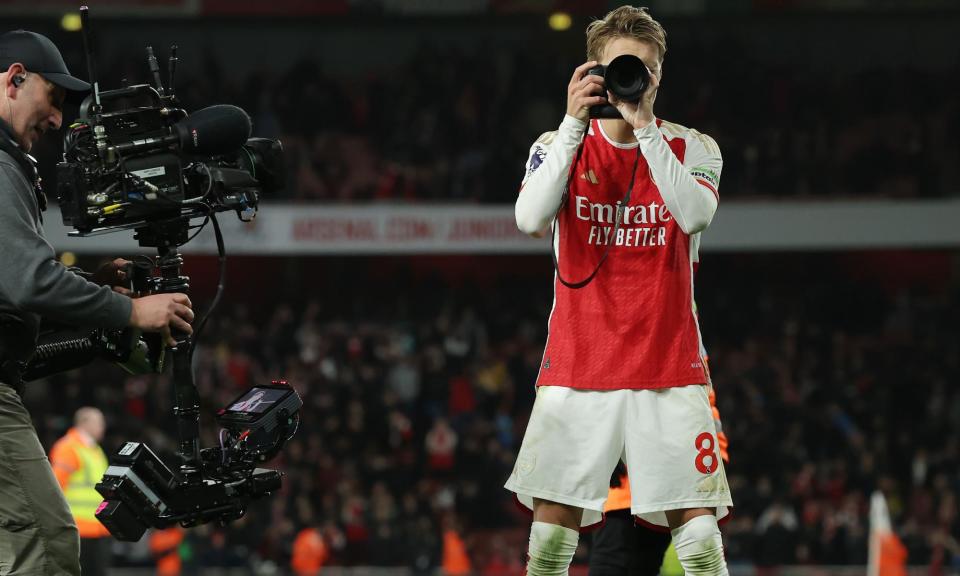 <span>Arsenal captain Martin Ødegaard celebrates the win over Liverpool by grabbing a camera and taking a picture of club photographer Stuart Macfarlane.</span><span>Photograph: Tom Jenkins/The Guardian</span>