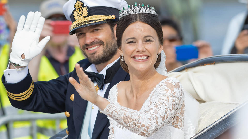 STOCKHOLM - JUN 13, 2015: Prince Carl-Philip and Princess Sofia laughing and waving in the royal carriage after the wedding with the crowd cheering.