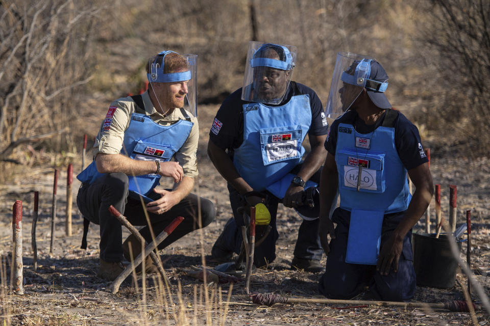 Britain's Prince Harry with Jose Antonio, center, of the Halo Trust and a mine clearance worker walk through a minefield in Dirico, Angola Friday Sept. 27, 2019, during a visit to see the work of landmine clearance charity the Halo Trust, on day five of the royal tour of Africa. Prince Harry is following in the footsteps of his late mother, Princess Diana, whose walk through an active mine field in Angola years ago helped to lead to a global ban on the deadly weapons. (Dominic Lipinski/Pool via AP)