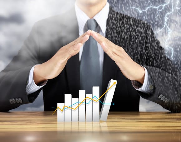 Businessman holding hands over chart in midst of storm