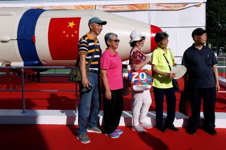 Visitors pose in front of a Changzheng-1 (CZ-1) or Long March 1 rocket displayed at a high-tech fair, to celebrate the 20th anniversary of the territory's handover to Chinese rule, in Hong Kong, China. REUTERS/Bobby Yip